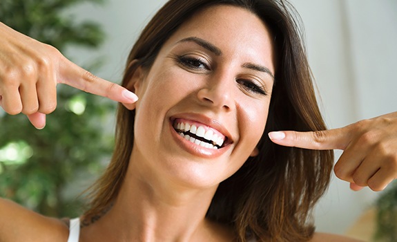 Woman pointing to her smile after gum disease treatment