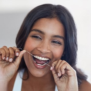 Woman smiling while flossing her teeth