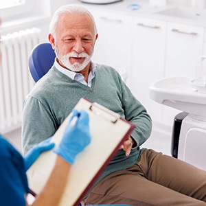 older man sitting in a dentist’s chair having a consultation