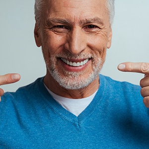 older man smiling and pointing to his mouth 