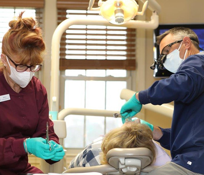 Patient receiving dental checkup and teeth cleaning from dentist and team member