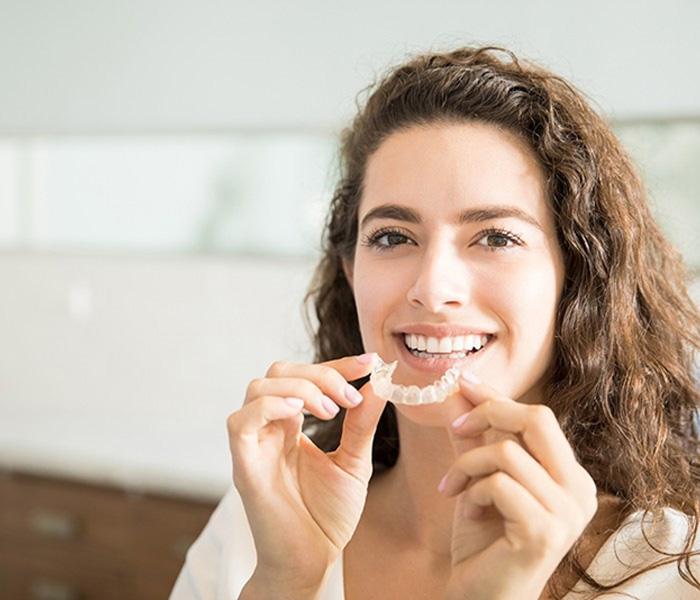 Woman with brown, curly hair holding ClearCorrect aligner