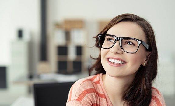 Closeup of woman with glasses smiling in her apartment