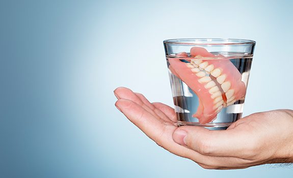 Full set of dentures in glass of water