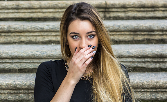 Woman in need of periodontal treatment covering her mouth