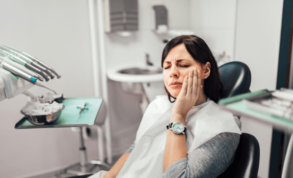 Woman holding cheek before emergency dentistry