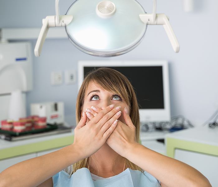 Fearful patient in need of sedation dentistry covering her mouth