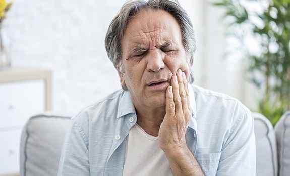 Man in need of T M J therapy holding jaw