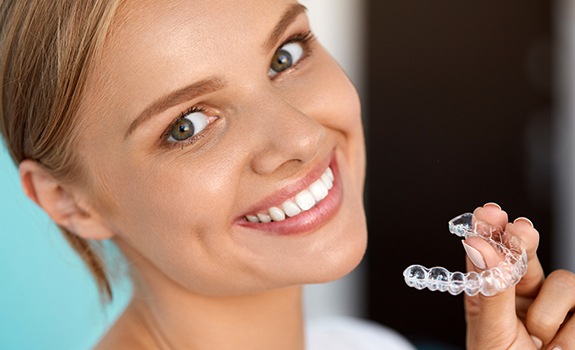 Smiling woman holding an Invisalign tray