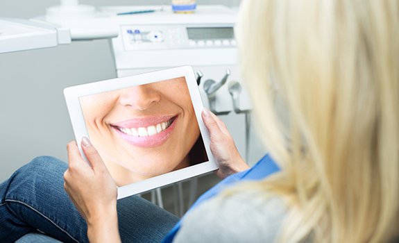 Woman looking at her virtual smile design on tablet computer