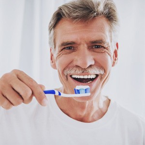 Man in white shirt about to brush his teeth