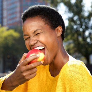 Woman in yellow shirt about to eat an apple