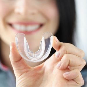 Woman holding up a clear plastic mouthguard