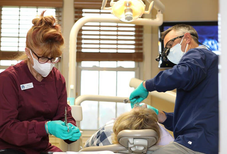 Dentist and team member treating dental patient