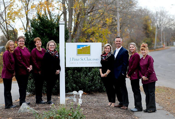 Doctor Saint Clair and his dental team by dental office sign