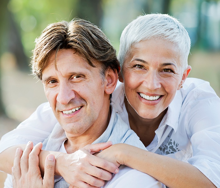 Man and woman smiling after porcelain dental crown and fixed bridge treatment