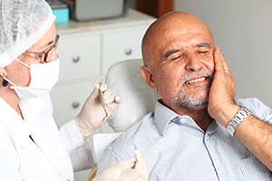 Man in dental chair holding cheek