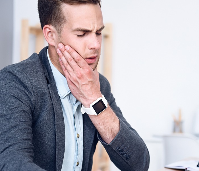 Man in need of T M J therapy holding jaw