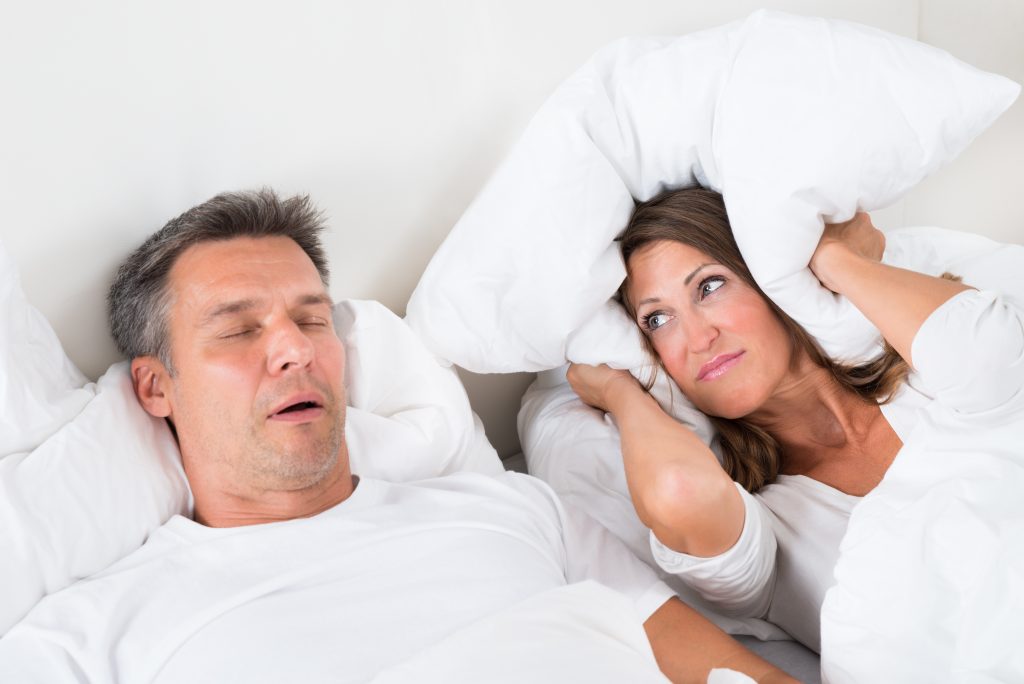 man snoring while partner covers ears