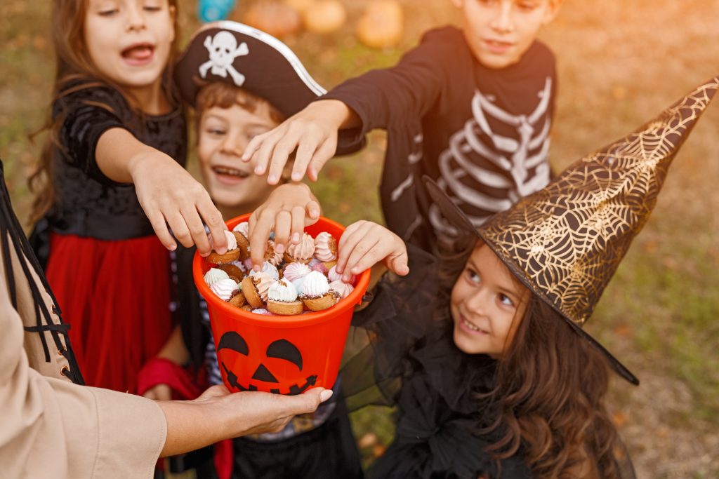 children grabbing Halloween candy from bucket 