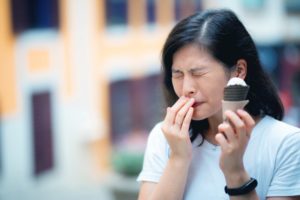 Woman with sensitive teeth and ice cream should visit Rowley dentist