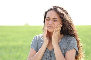Woman with jaw pain due to TMJ disorder